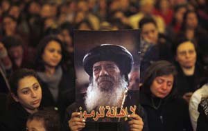 Mourners hold up a picture of Pope Shenouda III, who has died.