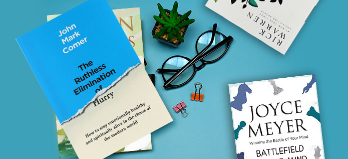 Inspirational authors book laying flat with glasses and cactus on light blue table 